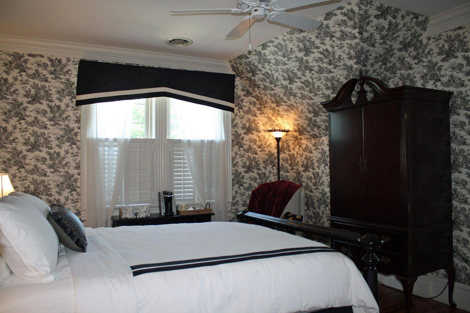 View of bed and television cabinet with window in background